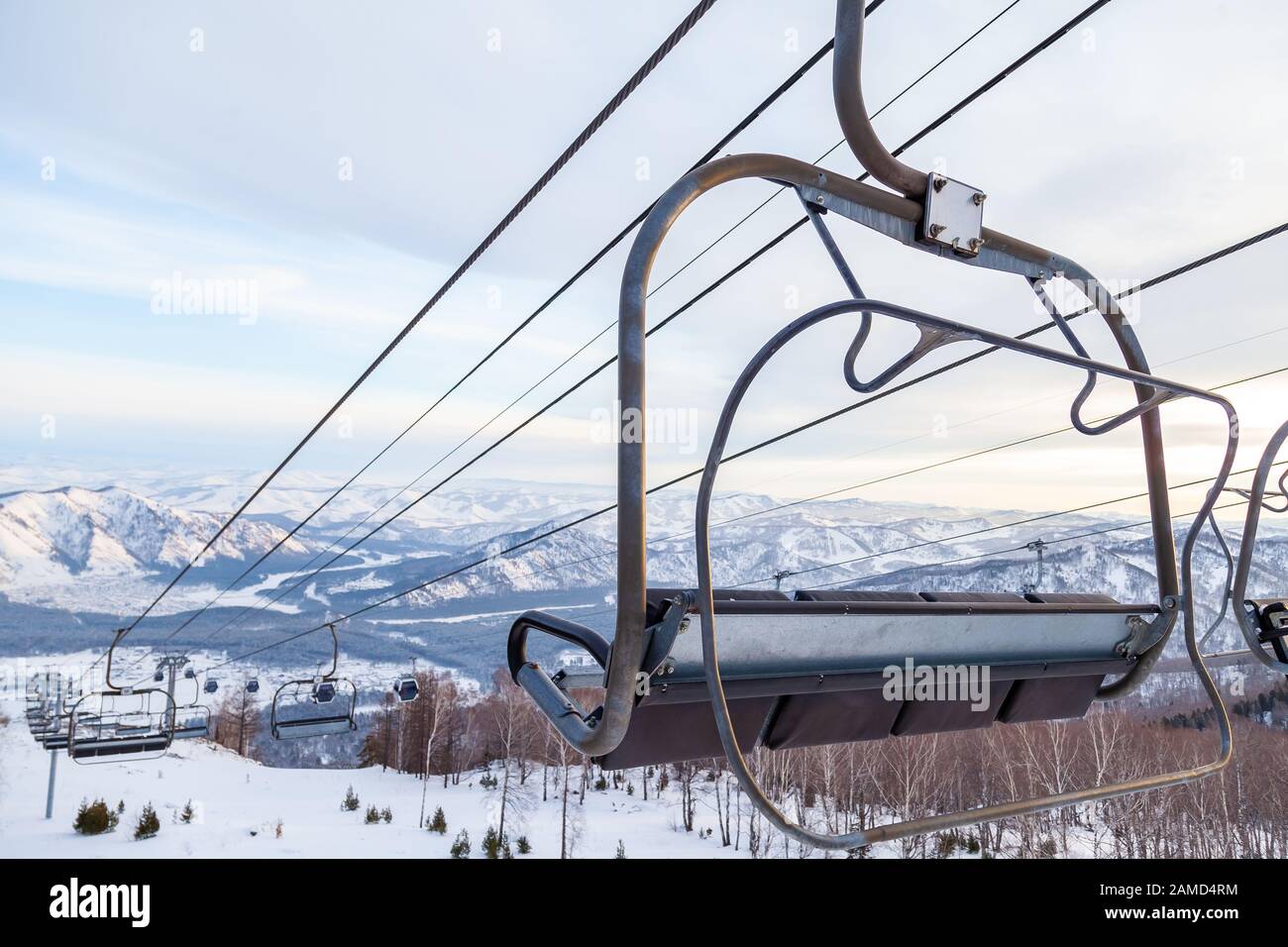 Un télésiège à télécabine avec cabine suspendue sur un câble dans lequel se trouvent des personnes avec skis et snowboards sur un fond de montagnes, arbres avec sno Banque D'Images
