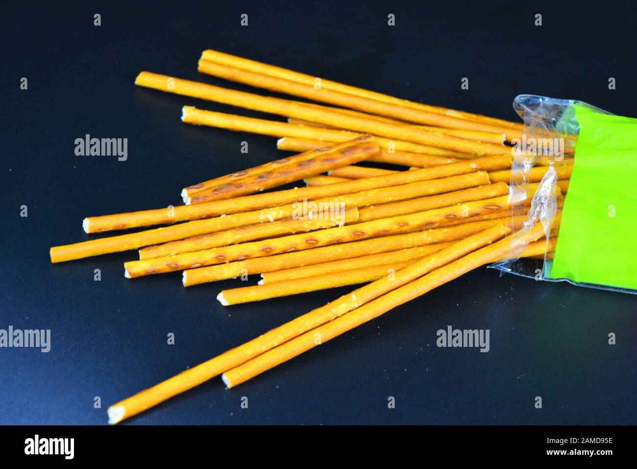 Pailles savoureuses et salées à base de sel à base de farine, sautées dans des emballages saupoudrés sur fond en plastique noir. Banque D'Images