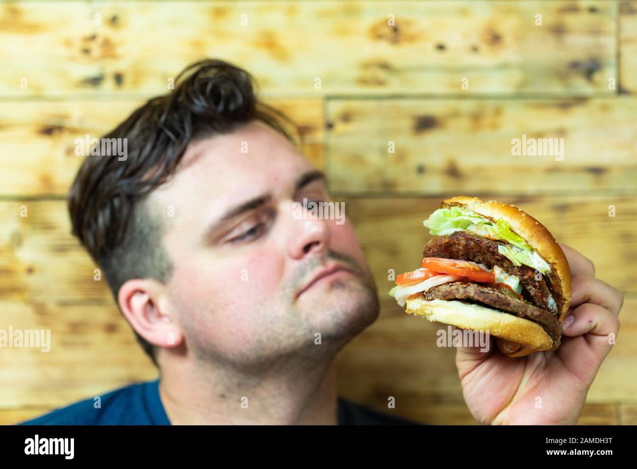 Bon homme jeune sur le point de profiter de son hamburger. Des repas rapides. Banque D'Images