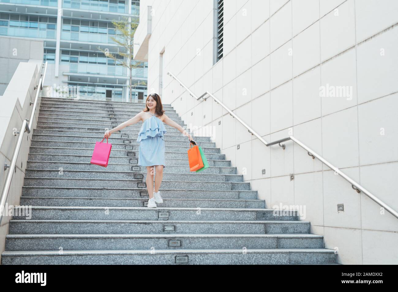 Cheerful woman en descendant les escaliers avec devantures colorées des paquets. Concept et de la mode Banque D'Images