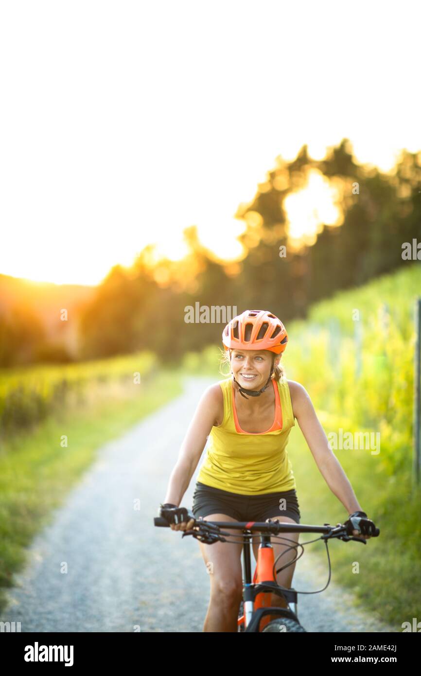 Jolie jeune femme cycliste sur un vélo de montagne bénéficiant d'un mode de vie actif sain en plein air en été (shallow DOF) Banque D'Images