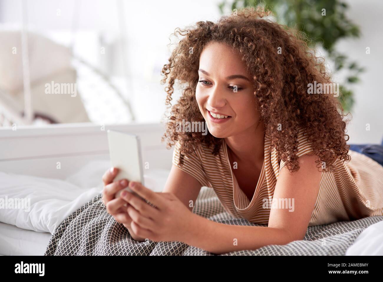 Belle femme utilisant un smartphone dans le lit Banque D'Images