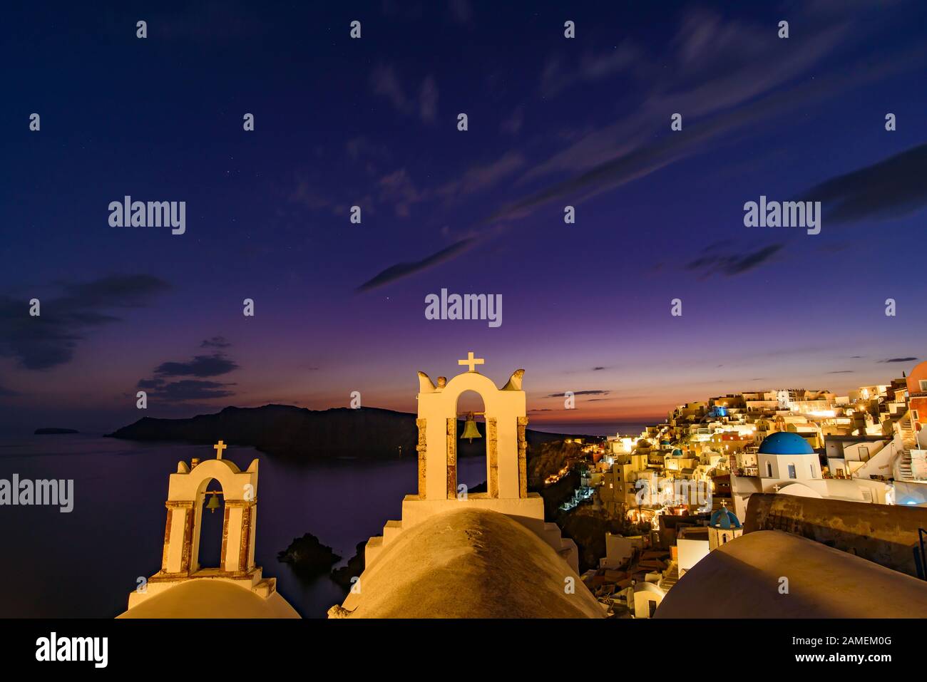 Églises à dôme bleu et clocher face à la mer Égée avec lumière chaude au coucher du soleil à Oia, Santorin, Grèce Banque D'Images