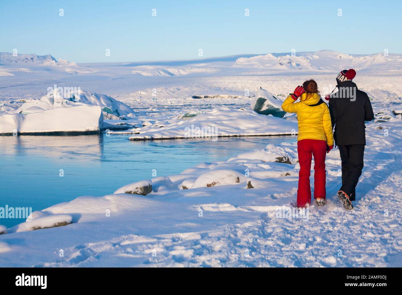 Couple touristes marchant en admirant le paysage magnifique de la lagune Glaciaire de Jokulsarlon, au bord du parc national de Vatnajokull, Islande en janvier Banque D'Images