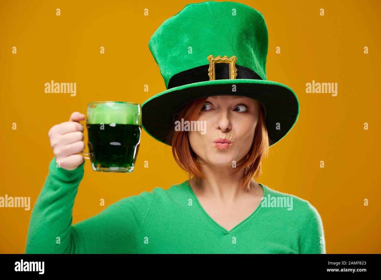 Femme ludique avec chapeau de leprechaun regardant la bière Banque D'Images