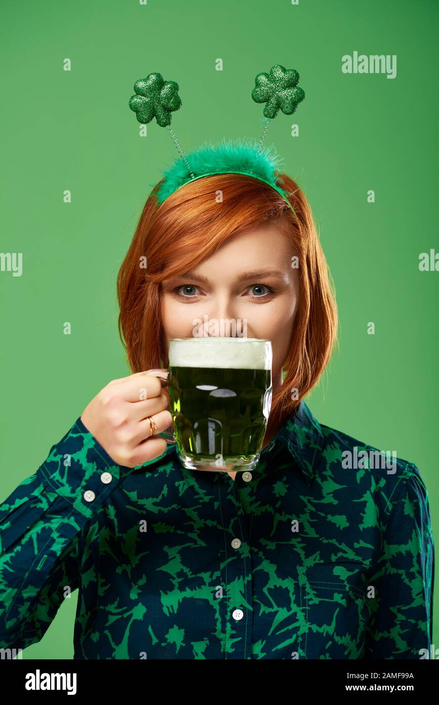 Portrait de la jeune femme qui boit de la bière en studio Banque D'Images