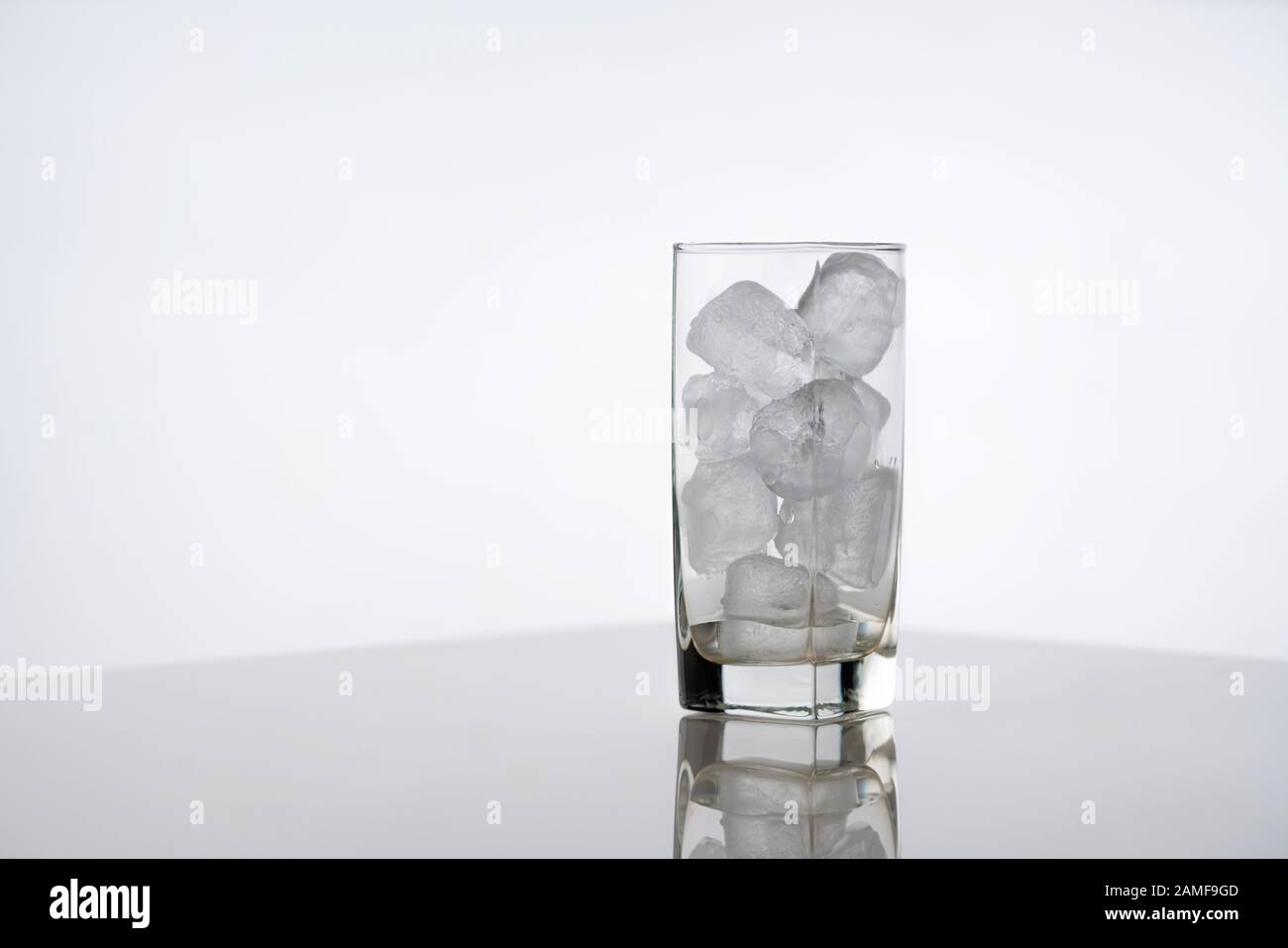 Verre plein de glace sur fond blanc. Verre glacé avec glaçons sans boisson, préparation avant de mélanger un cocktail Banque D'Images
