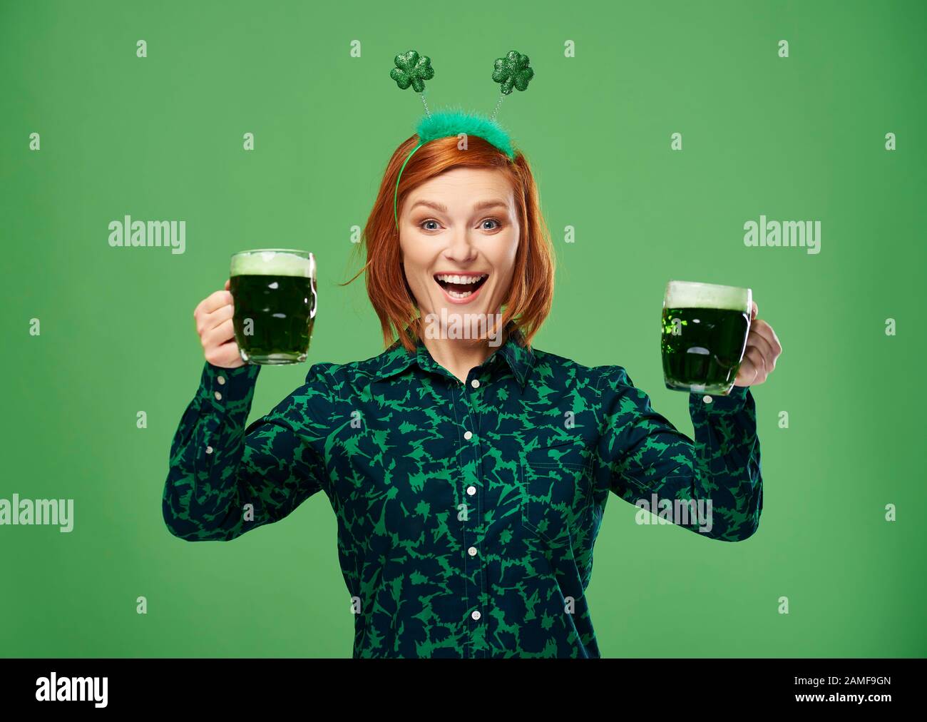 Une femme excitée avec de la bière fait un toast en studio Banque D'Images
