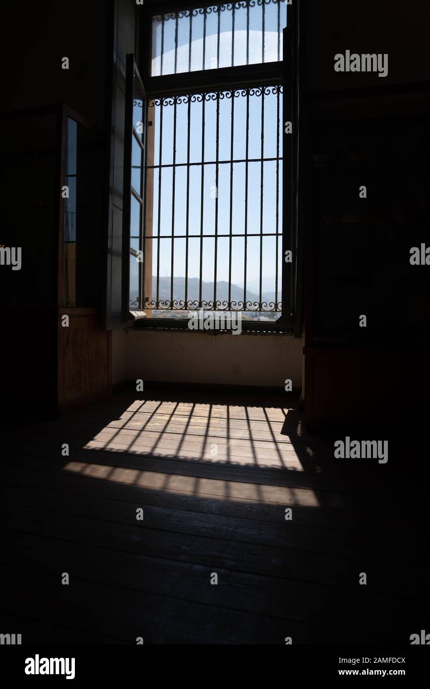 Ombres formées sur le sol en pierre du soleil se faisant passer par le gril de sécurité dans la fenêtre avec le ciel bleu à l'extérieur. Banque D'Images