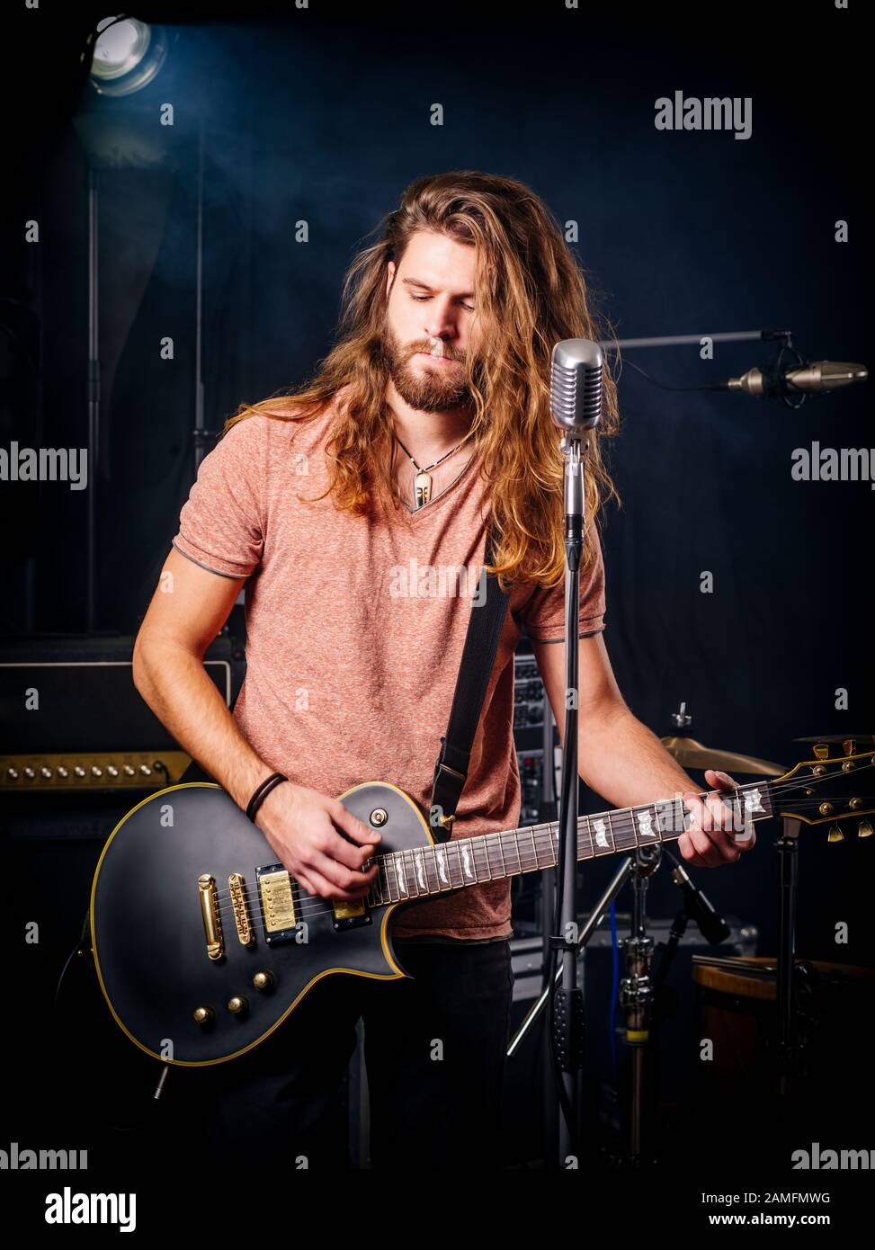 Photo d'un jeune homme aux cheveux longs et la barbe playing electric guitar sur scène. Banque D'Images
