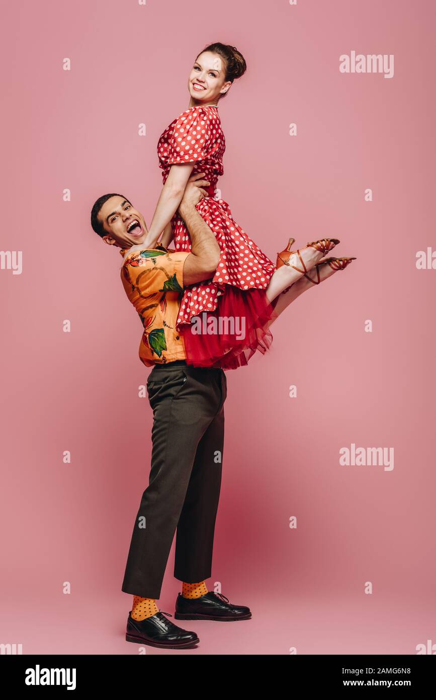 danseuse gaie tenant partenaire tout en dansant boogie-woogie sur fond rose Banque D'Images