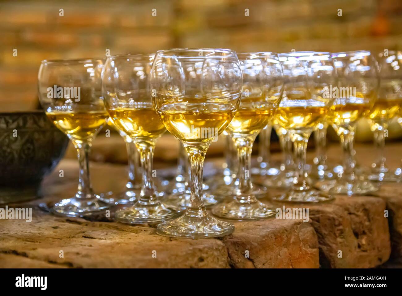 Rangées de gobelets en verre transparent pour vin rempli de vin d'ambre sur une surface en pierre Banque D'Images