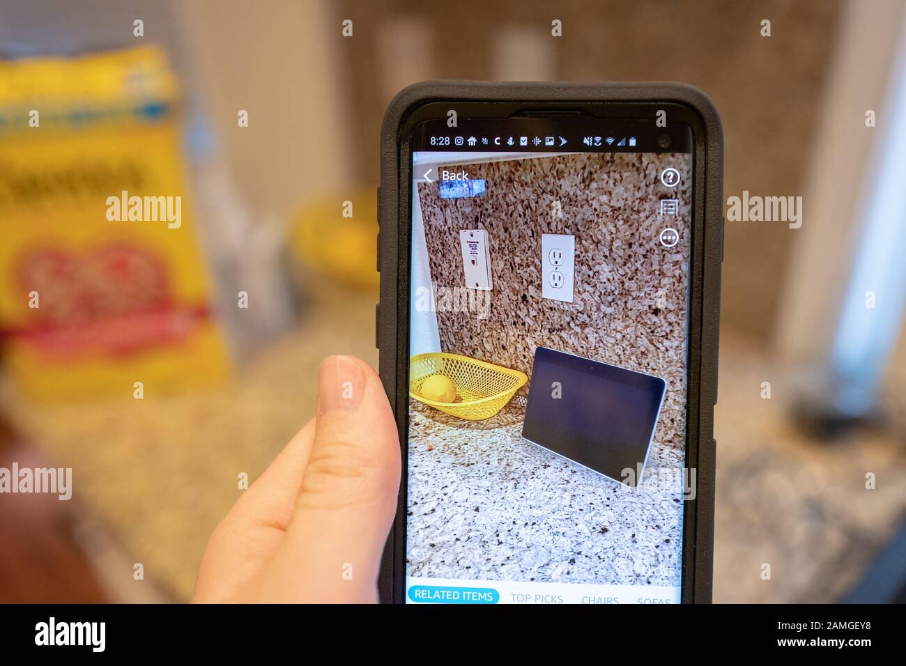 Main d'un homme tenant un smartphone et utilisant les fonctionnalités De Réalité augmentée dans l'application Amazon shopping pour visualiser un appareil Amazon Echo Show sur un comptoir de cuisine, San Ramon, Californie, 22 novembre 2019. L'AR est de plus en plus utilisée comme une fonctionnalité pour les consommateurs de visualiser les produits dans leur maison avant de prendre une décision d'achat. () Banque D'Images