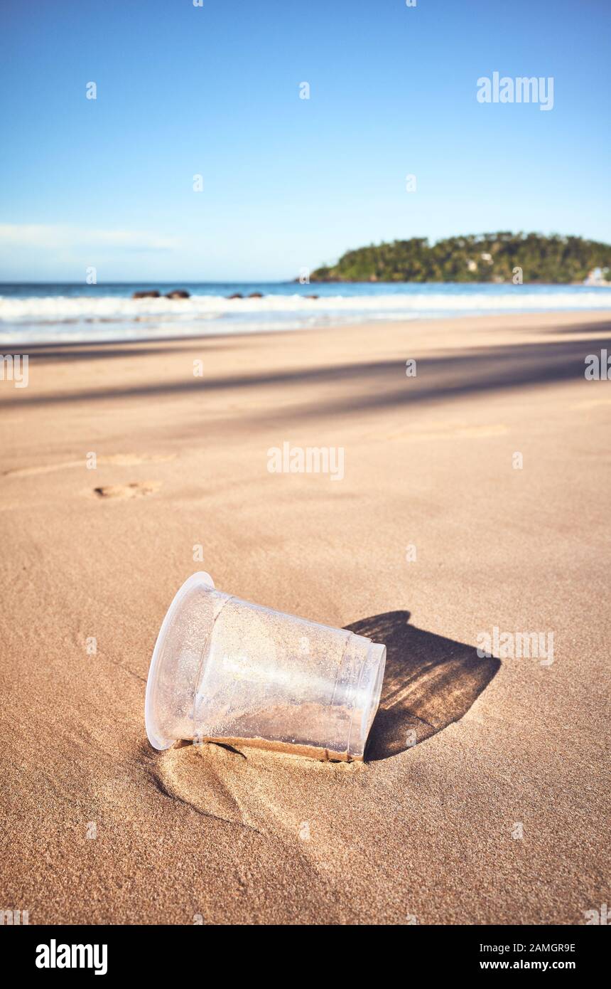 Tasse en plastique sur une plage tropicale, coloration appliquée, mise au point sélective. Banque D'Images