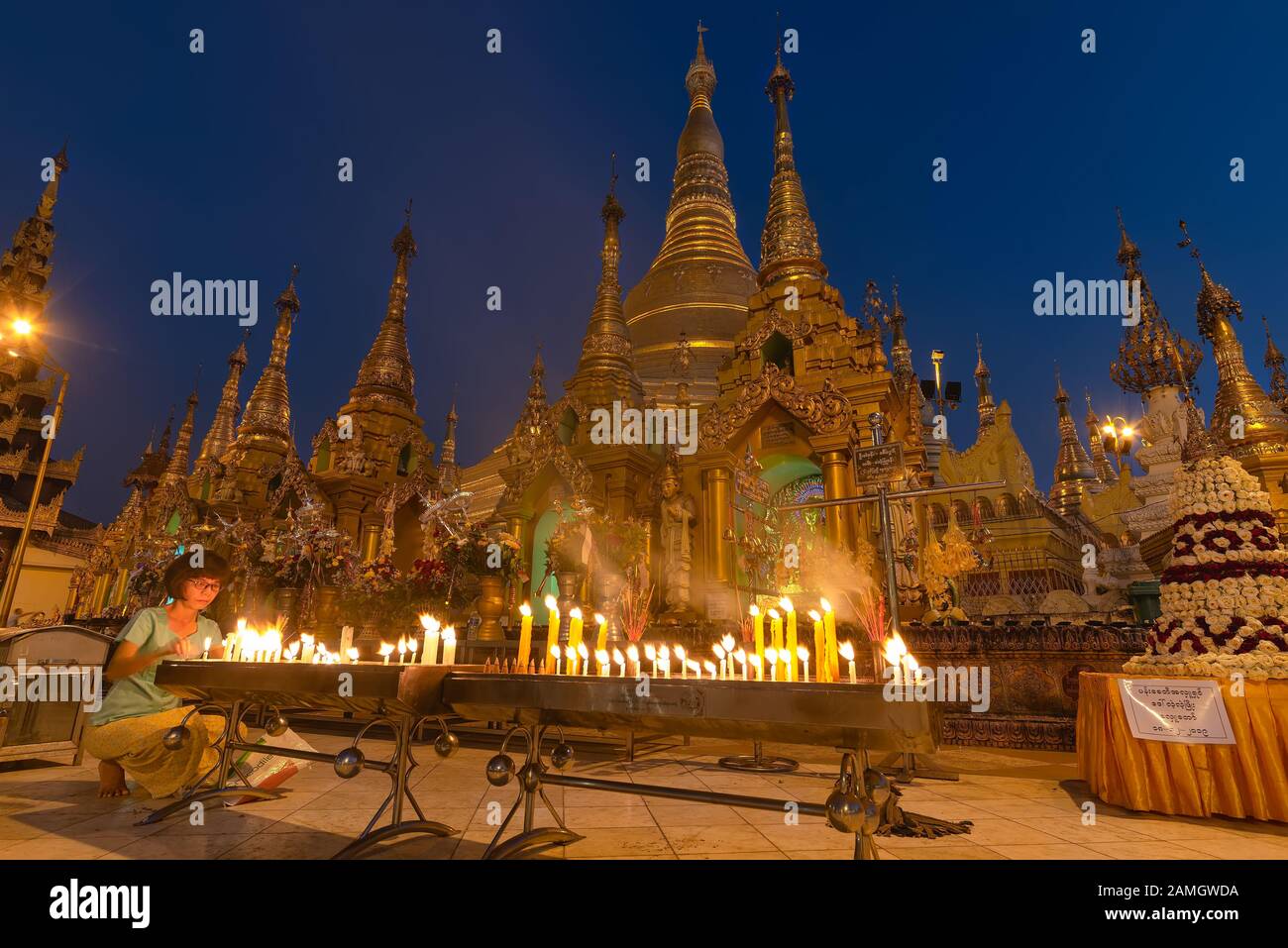 Yangon, Myanmar - 19 décembre 2019 : une femme bougie lumière en face de la pagode Shwedagon au crépuscule. Pagode Shwedagon pagoda est la plus sacrée de l'homme au Myanmar Banque D'Images