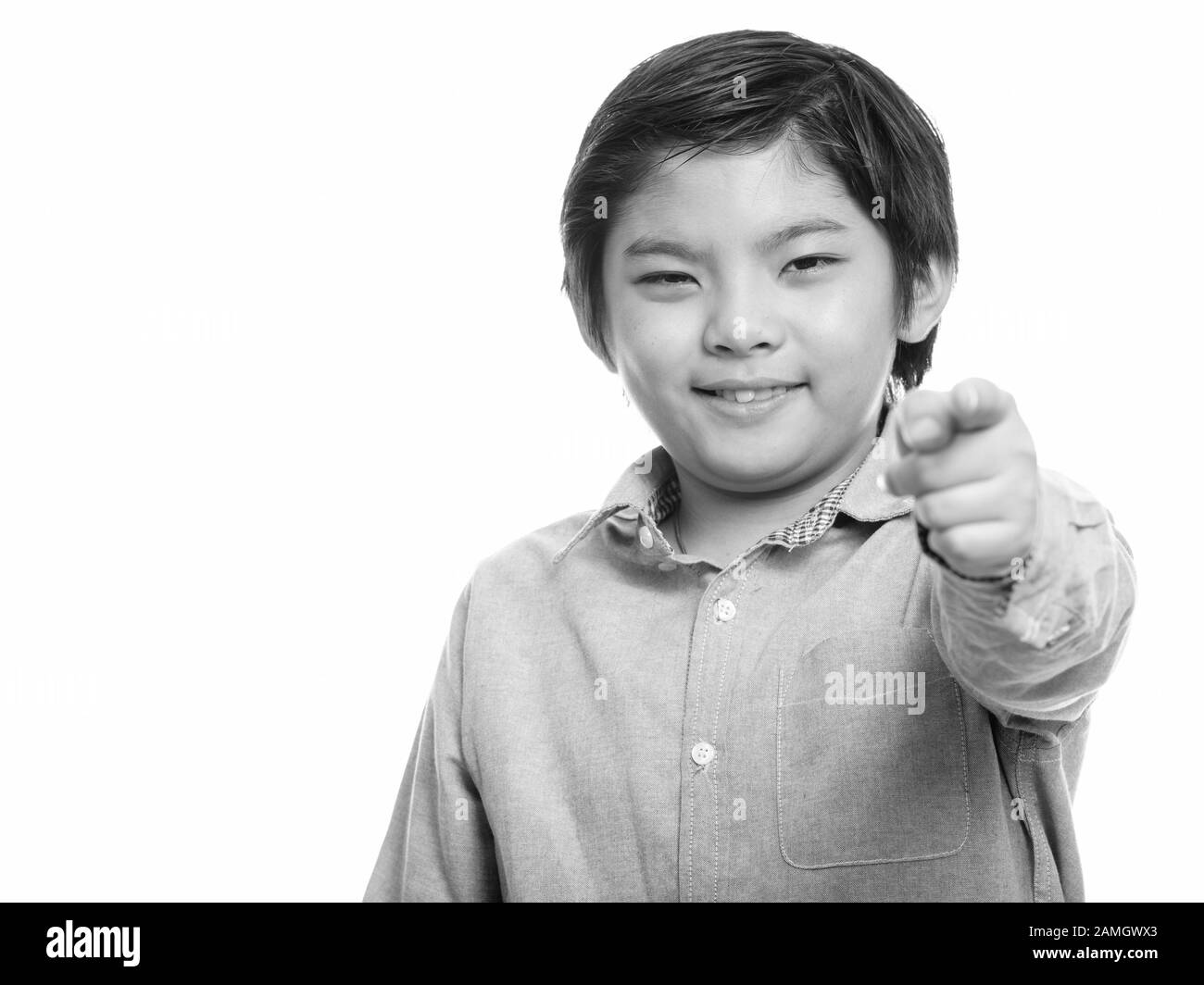 Studio shot of happy cute Japanese boy smiling while doigt at camera Banque D'Images