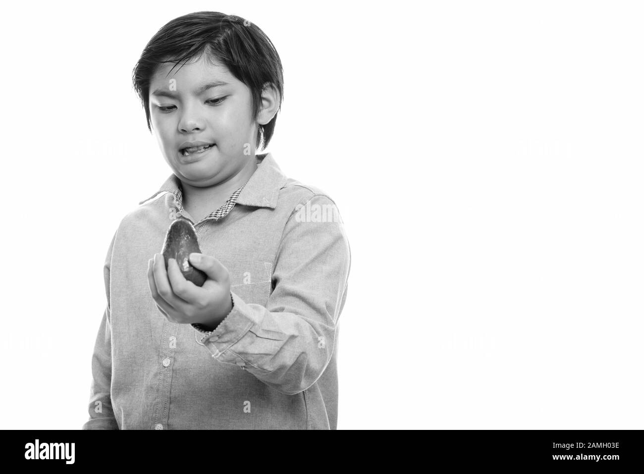 Studio shot of cute Japanese boy holding l'avocat et à la dégoûté Banque D'Images