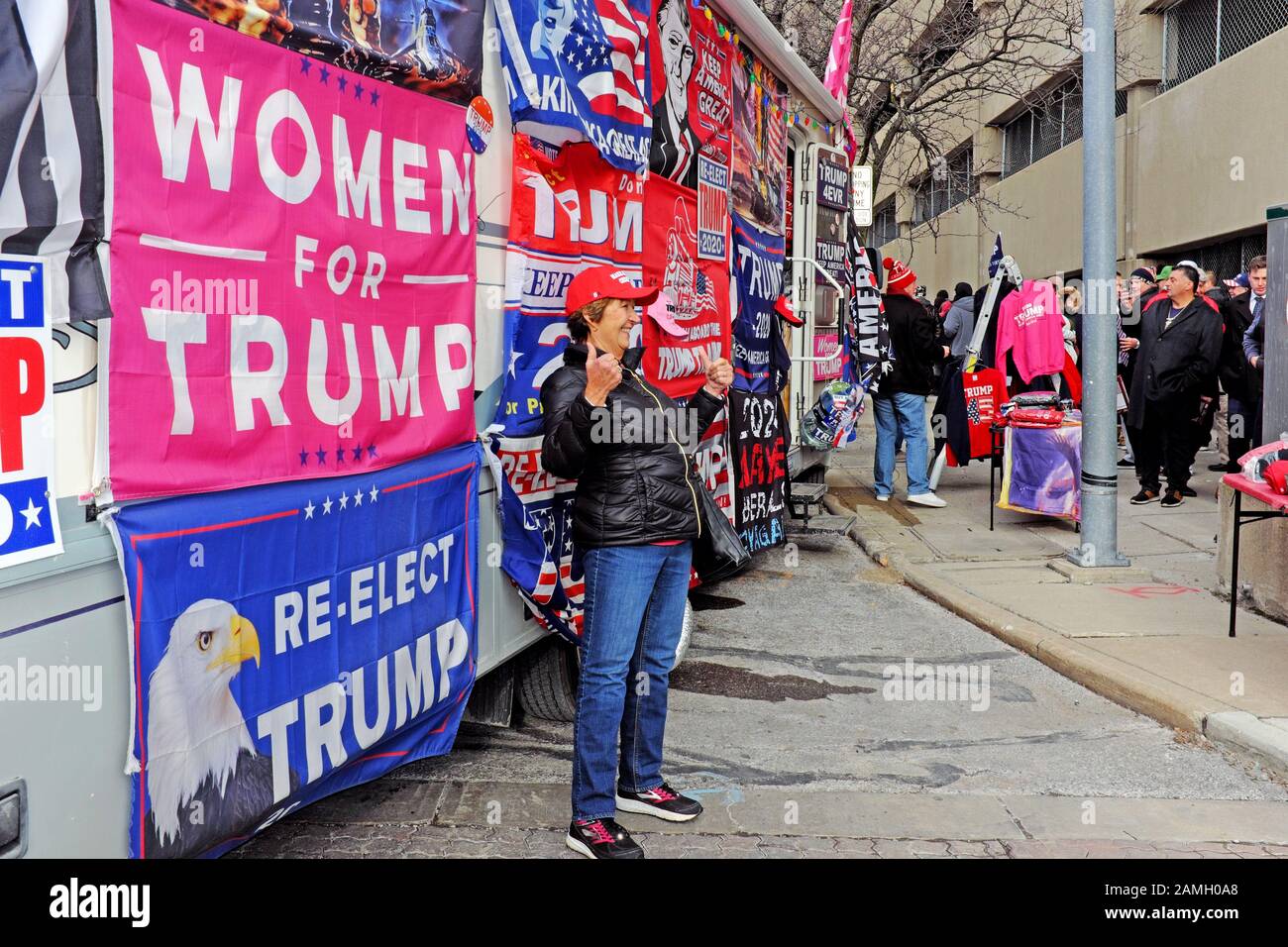 Un partisan d'Atout féminin pose pour une photo devant un bus en stationnement avec pro-Trump les enseignes et bannières à Toledo, Ohio, USA. Banque D'Images