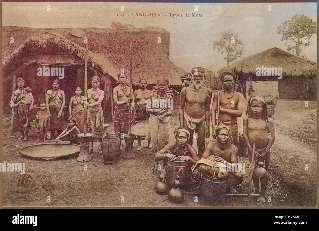 Carte postale gravée d'un groupe d'hommes, de femmes et d'enfants autochtones posant pour une photo de groupe devant leurs huttes de toit en chaume, Vietnam, publié par Edition la Pagode Saigon, 1906. De La Bibliothèque Publique De New York. Remarque : l'image a été colorisée numériquement à l'aide d'un processus moderne. Les couleurs peuvent ne pas être précises sur une période donnée. () Banque D'Images