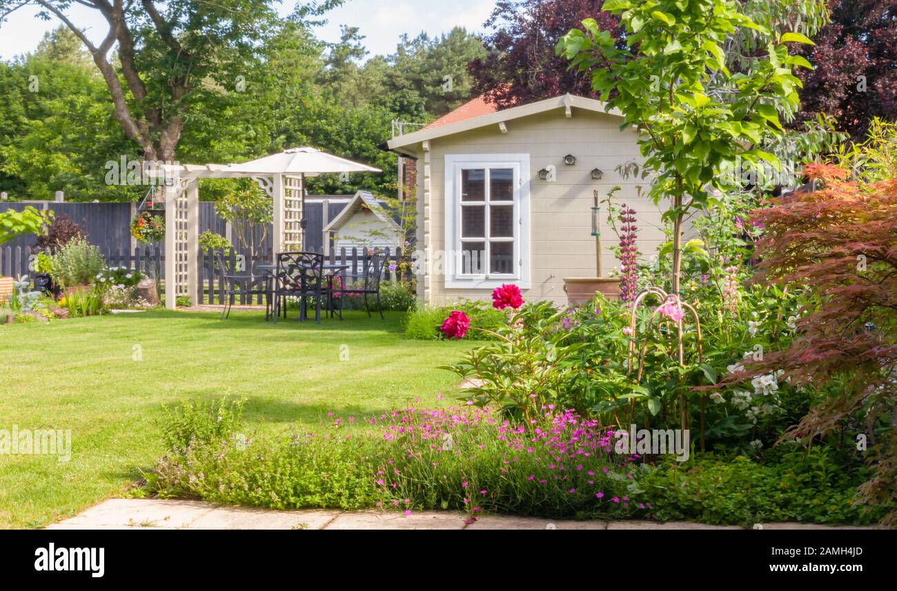 Jardin anglais en été avec la maison d'été avec arbres, plantes et fleurs. Banque D'Images