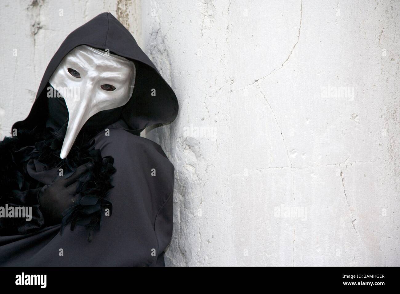 Homme masqué avec bec contre une colonne de marbre blanc à Venise Carnevale Banque D'Images