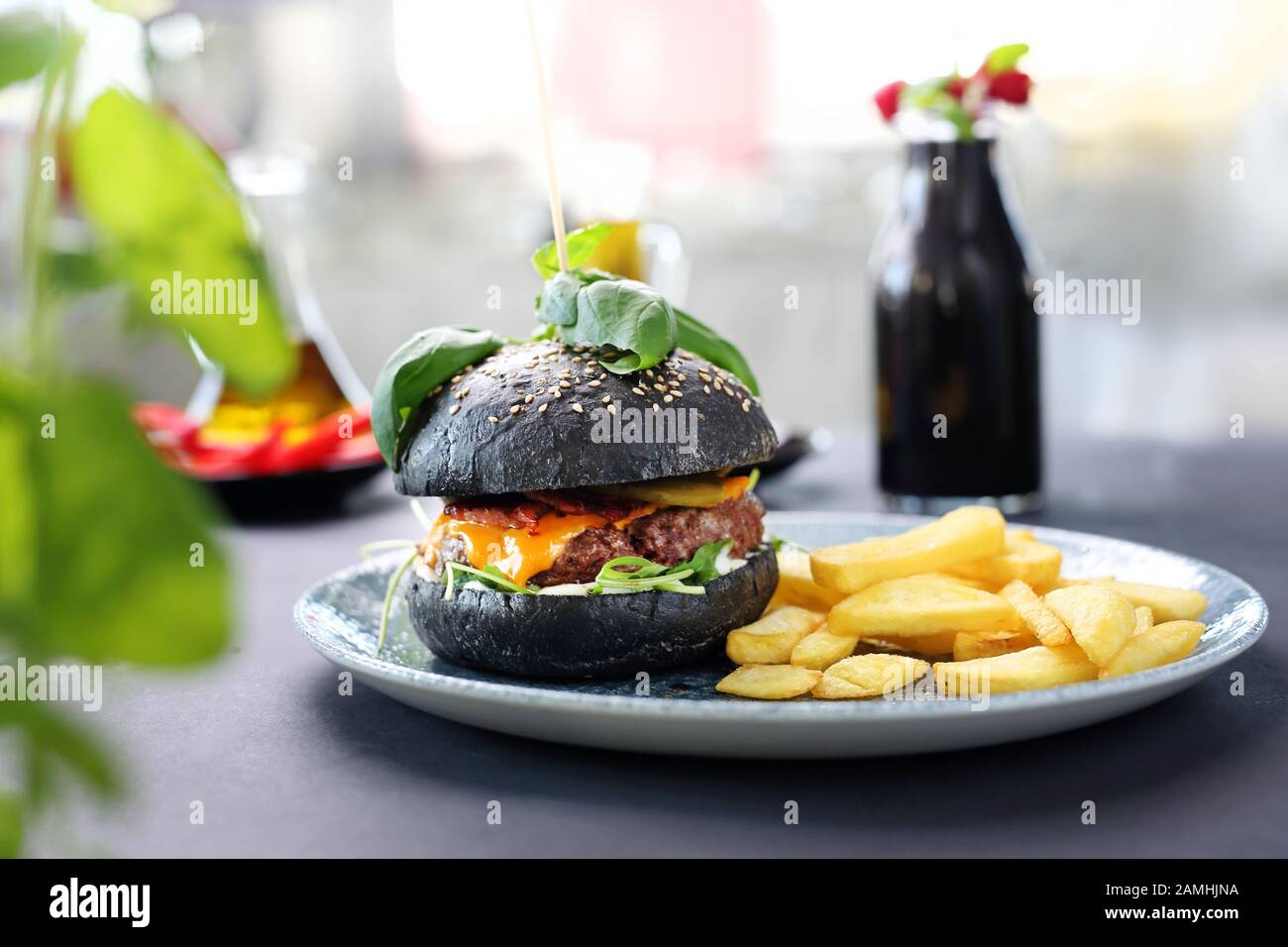 Hamburger noir. Un délicieux hamburger dans un rouleau noir. Banque D'Images