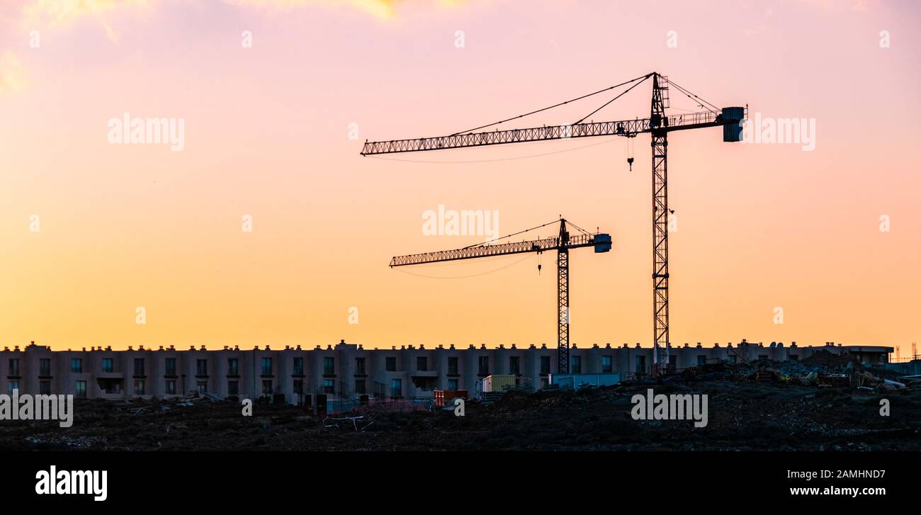 Deux grues de construction au coucher du soleil sur le développement du logement nouvellement construit près de la plage. Tejta Banque D'Images