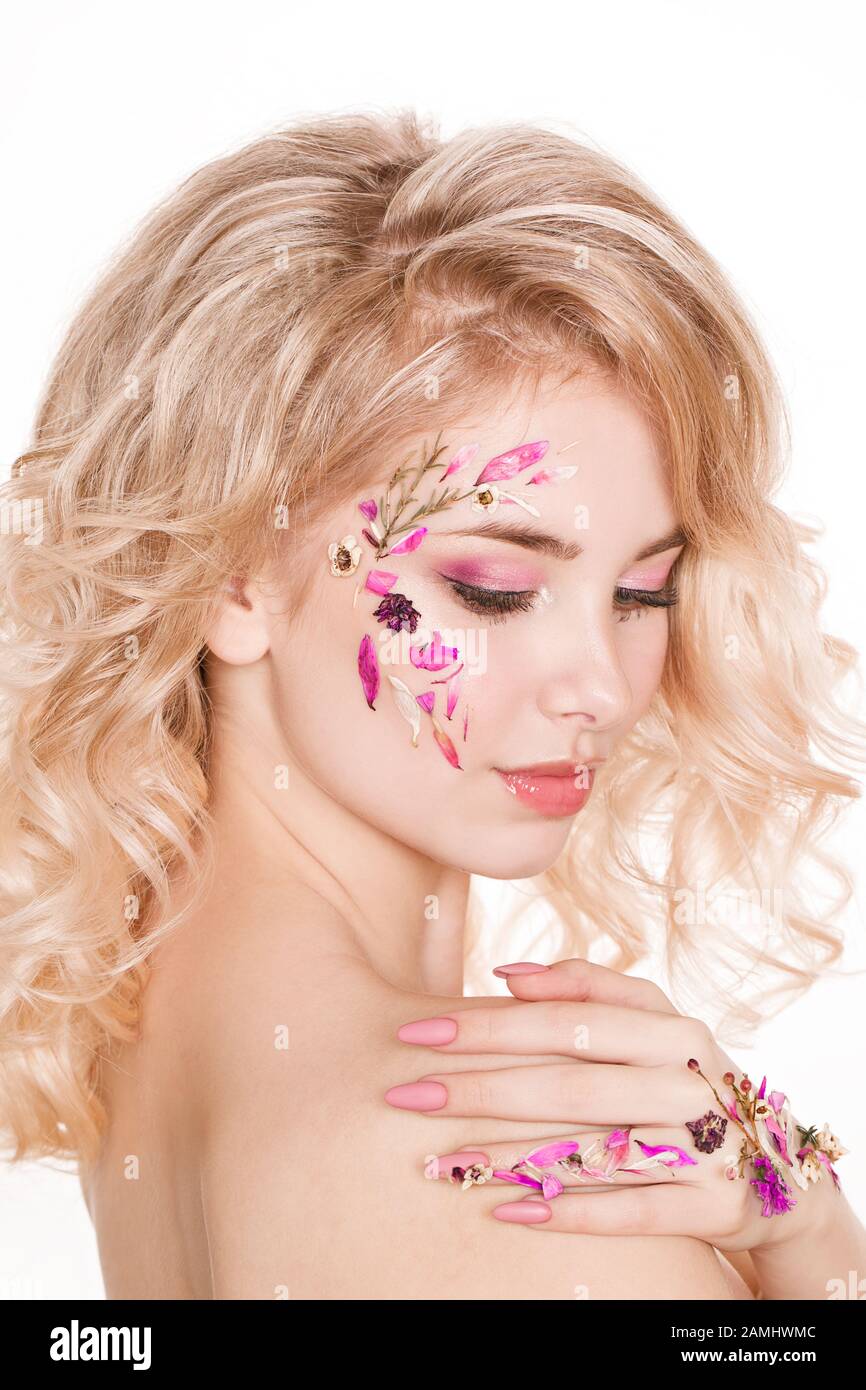 Cosmétiques et manucure. Portrait en gros plan d'une femme attrayante avec des fleurs sèches sur son visage, couleur pastel de la conception de l'ongle, maquillage et peau parfaits Banque D'Images