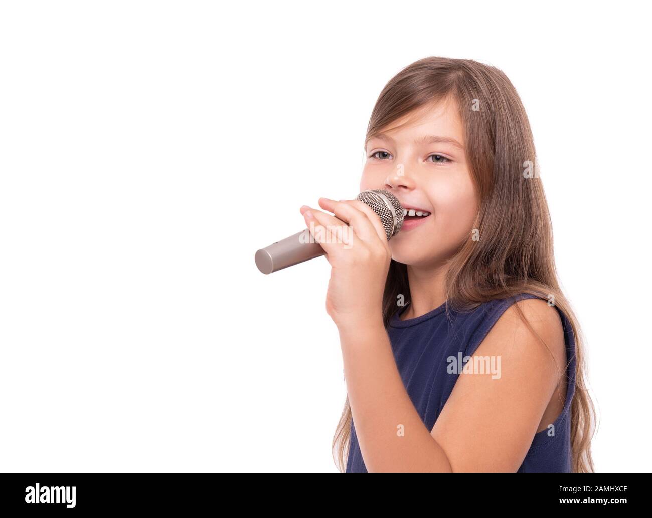 Petite fille posant avec un microphone pour chanter sur fond blanc. Banque D'Images