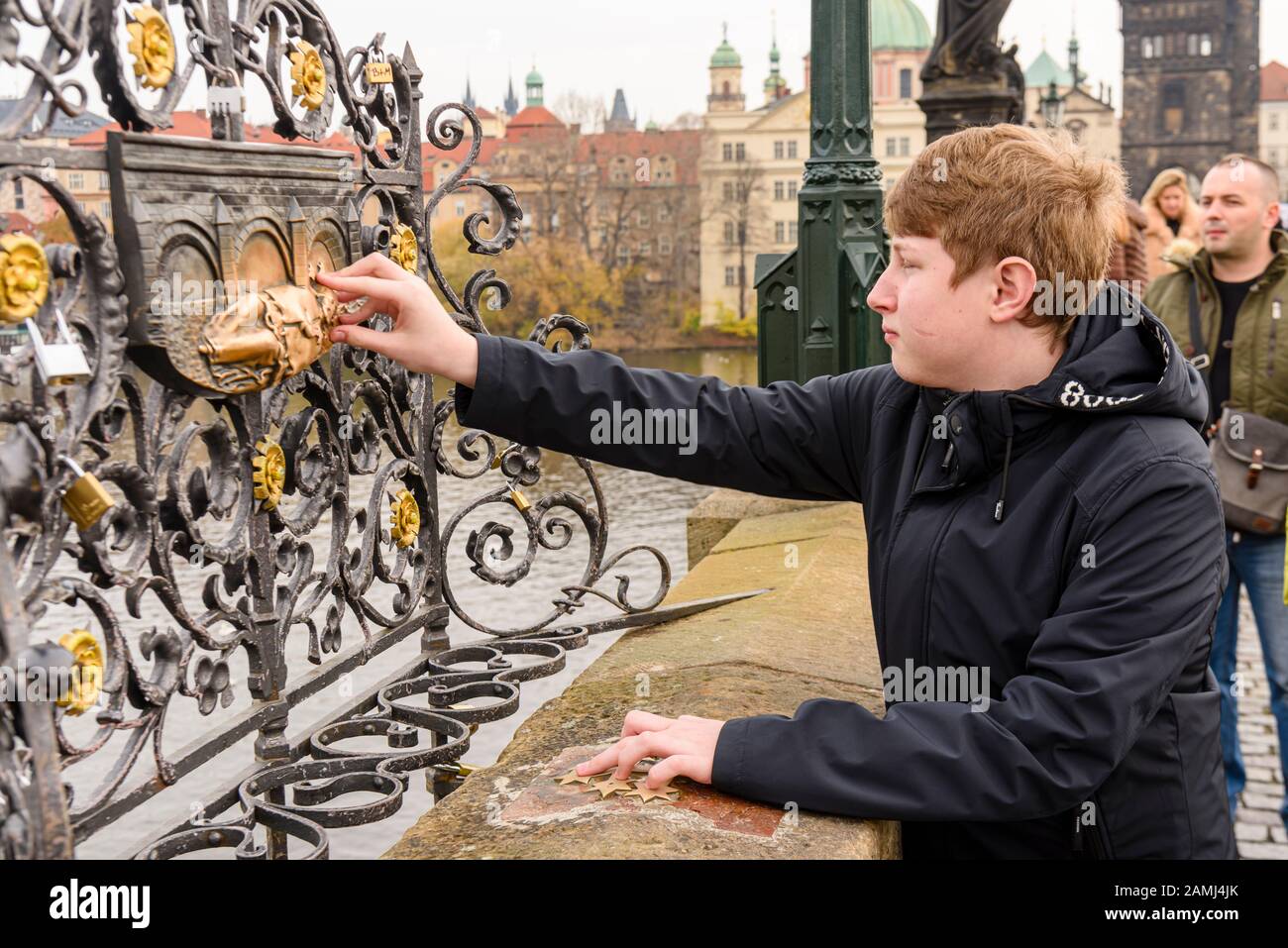 Un jeune homme place ses doigts sur les cinq étoiles de l'halo de la statue en laiton de Saint Jean de Nepomuk en priant, le pont Charles, Prague, République tchèque Banque D'Images