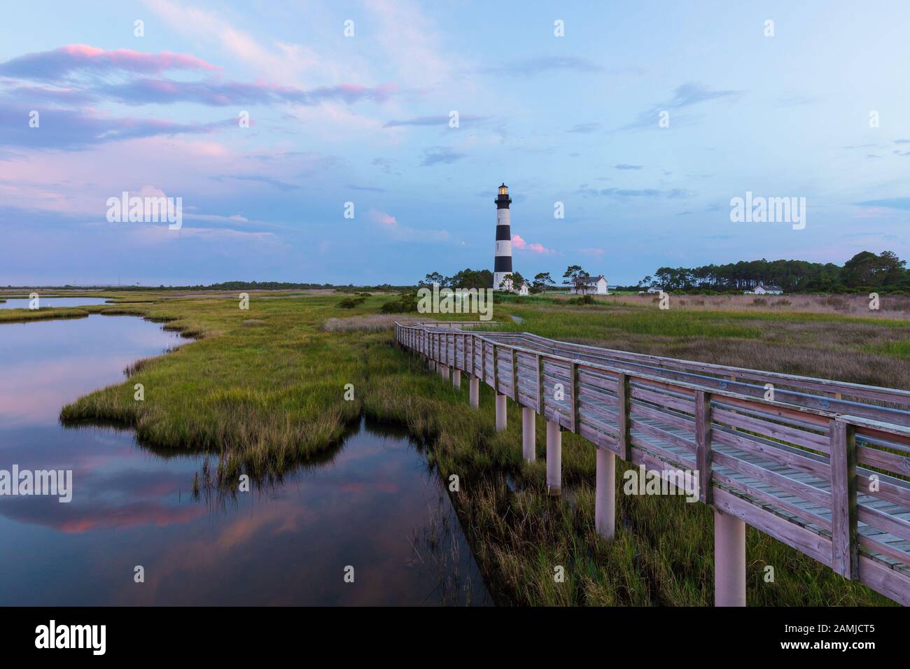 Coucher du soleil au phare de Bodie Island dans les Outer Banks, Caroline du Nord, avec promenade en bois en premier plan au-dessus du marais de l'océan Banque D'Images