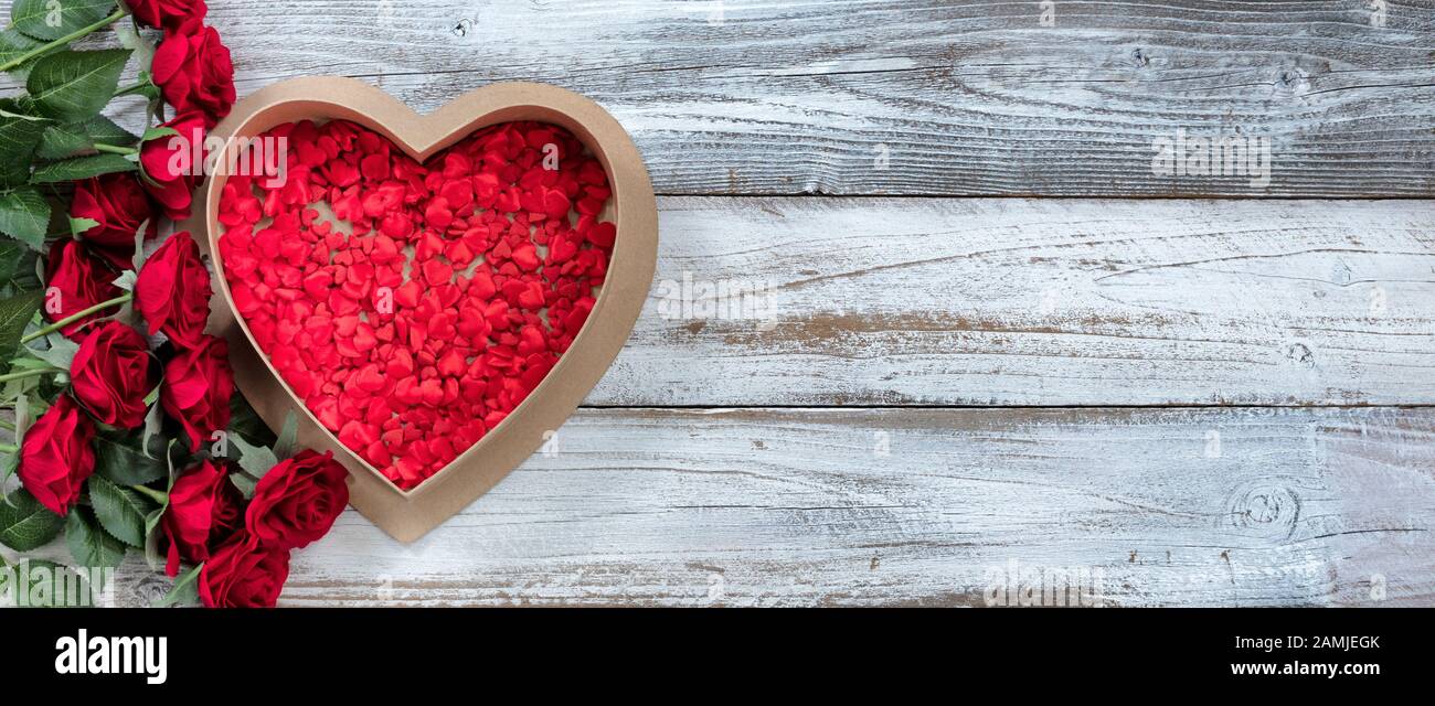 Bonne boîte cadeau de la Saint Valentin remplie de coeurs minuscules et de roses rouges sur bois rustique blanc Banque D'Images