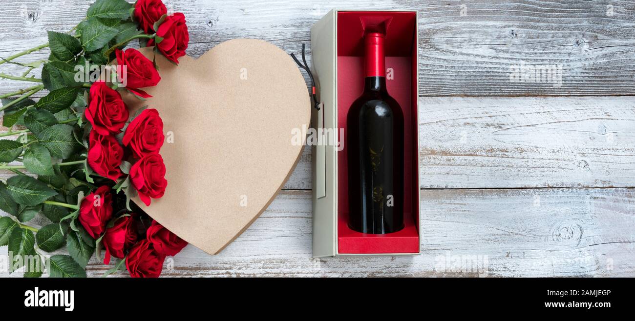 Joyeuses fêtes de la Saint Valentin avec vin, roses rouges et une boîte cadeau en forme de coeur sur bois rustique blanc Banque D'Images