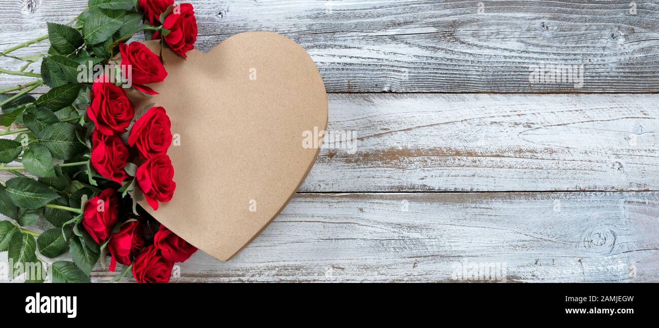 Bonne Saint Valentin avec roses rouges sur un coffret cadeau en forme de coeur avec fond blanc rustique en bois Banque D'Images