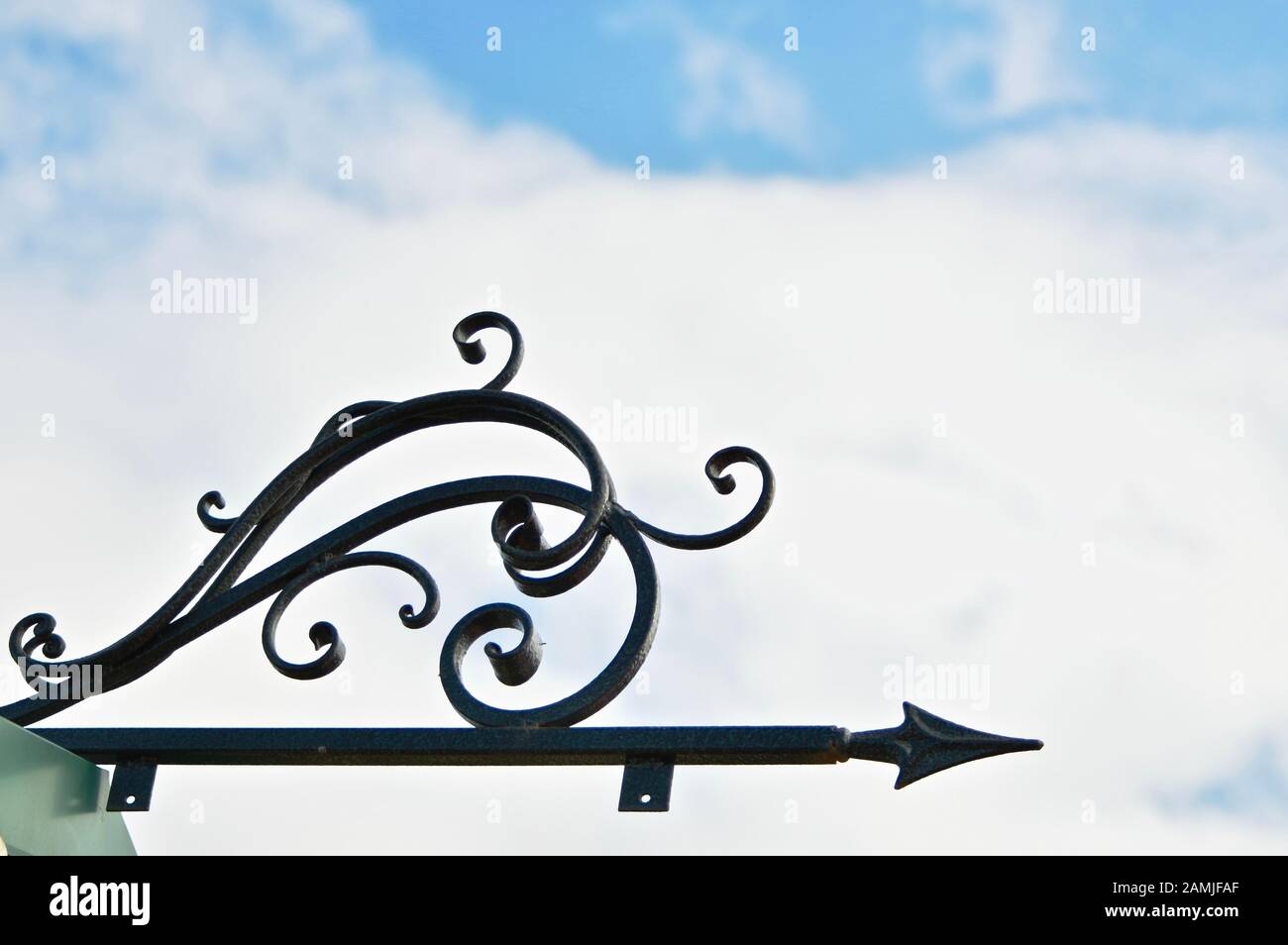 La flèche forgée est un pointeur vers la droite contre un ciel bleu nuageux. Banque D'Images