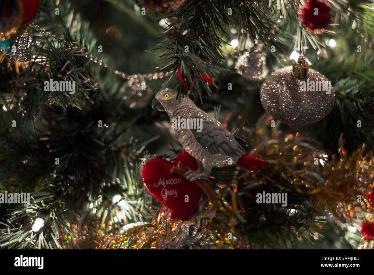 Gros plan d'un arbre de Noël décoré et éclairé avec des ornements gris africains et une boule d'argent. Banque D'Images