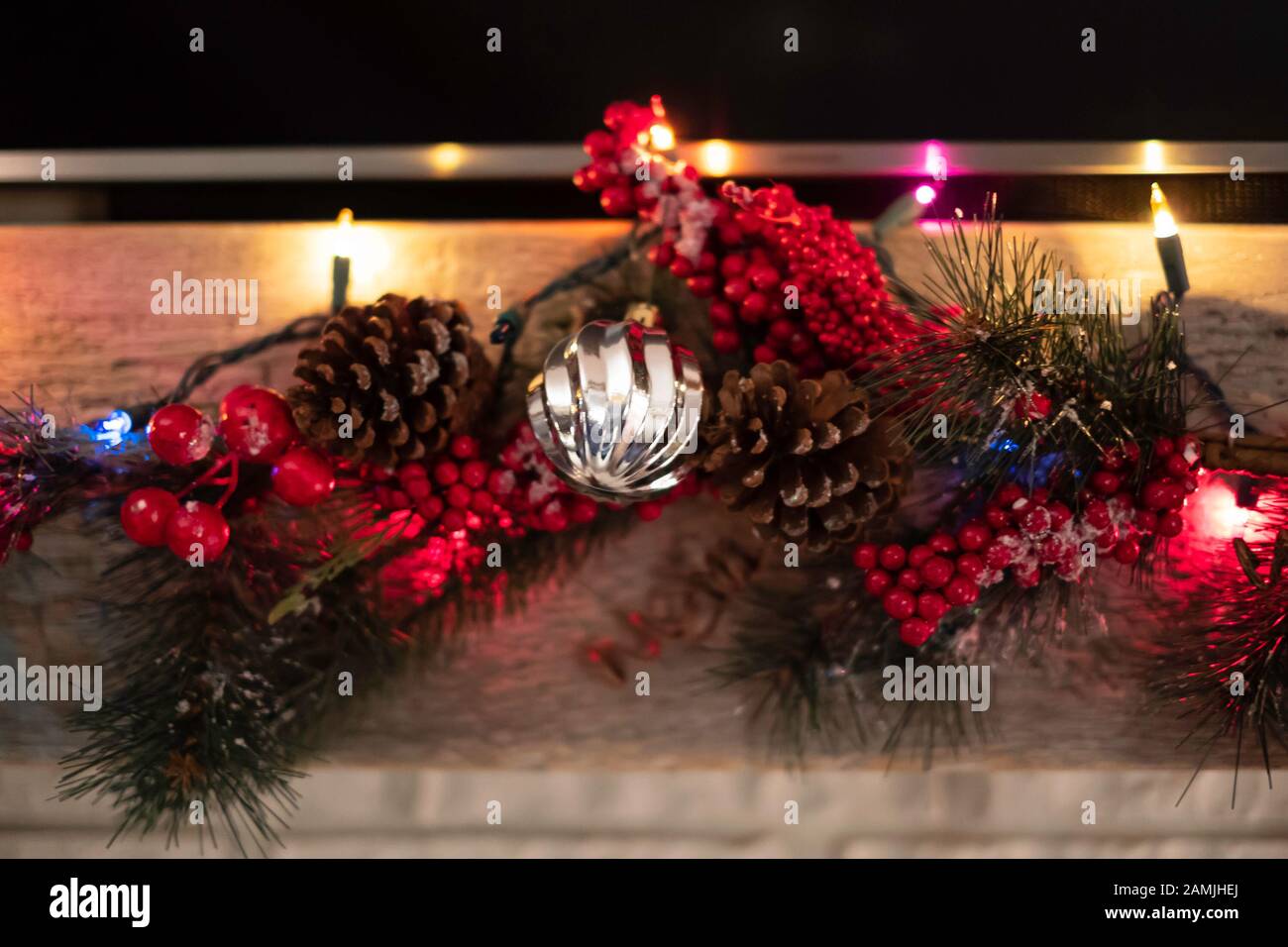 Un manteau de cheminée décoré avec des guirlandes de Noël en pin de rouges et de verts, de baies et de pinecones. Banque D'Images