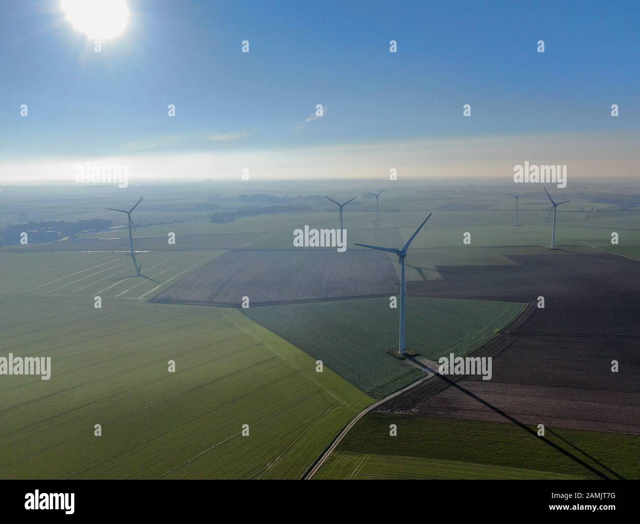 Vue aérienne des éoliennes sur les champs agricoles pendant la journée hivernale bleue. Production d'énergie avec des énergies propres et renouvelables. Banque D'Images