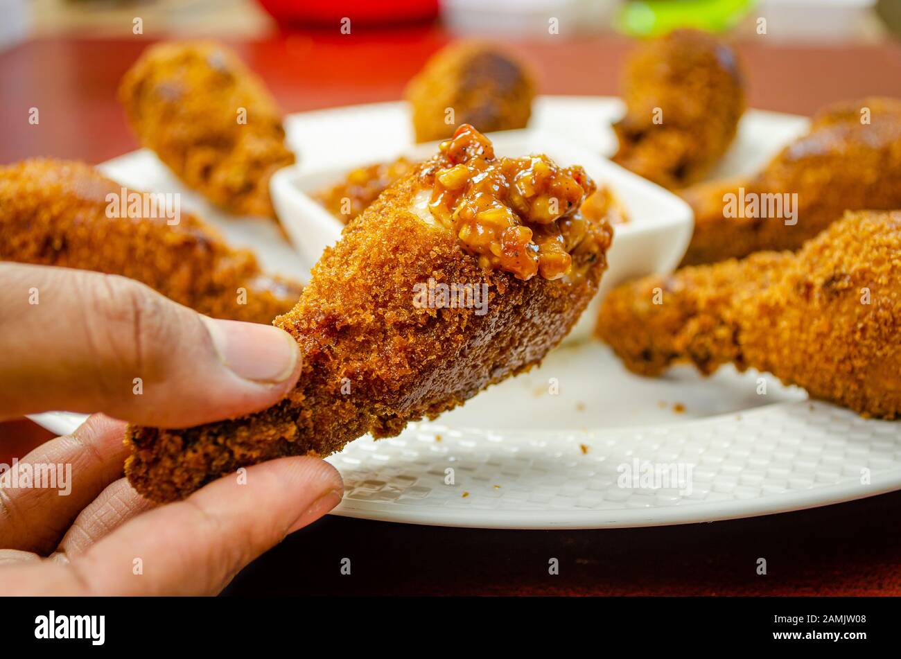 Main tenant un frire chaud et délicieux demi-bitten de jambe de poulet avec sauce trempée maison Banque D'Images