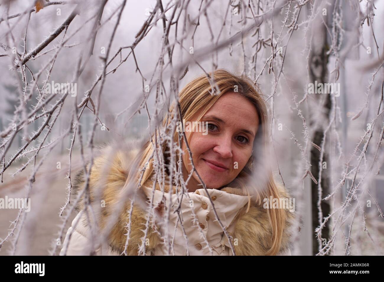 Portrait d'hiver de la jeune femme parmi les branches dépolies Banque D'Images