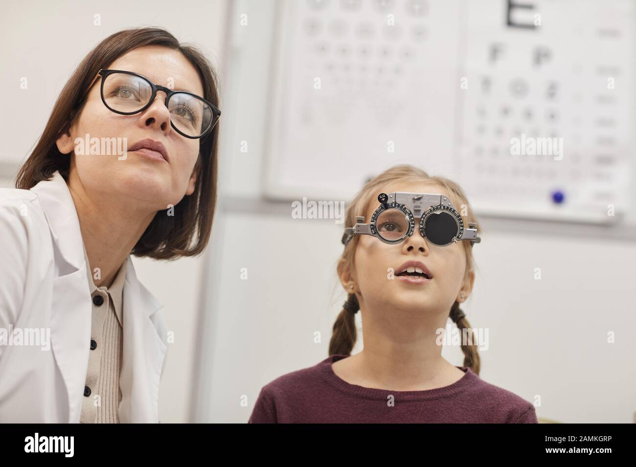 Portrait d'une jolie adolescente portant un cadre d'essai pendant le test de vision des enfants dans une clinique moderne d'ophtalmologie, espace de copie Banque D'Images