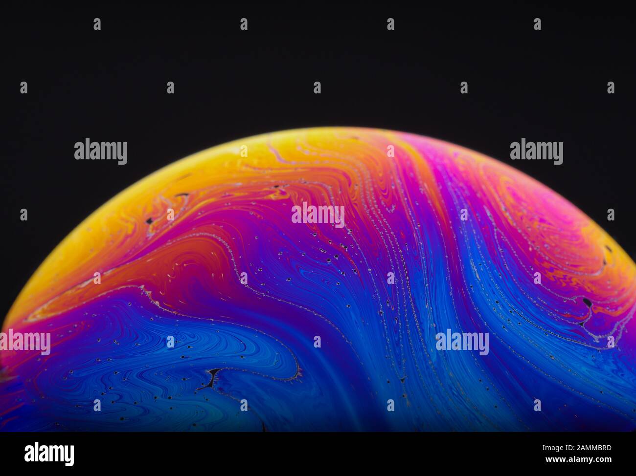Gros plan sur l'arc-en-ciel psychédélique de couleurs mélangeant et tourbillonnant dans une bulle de savon pour ressembler à une galaxie ou une planète fantasy isolé un fond noir Banque D'Images