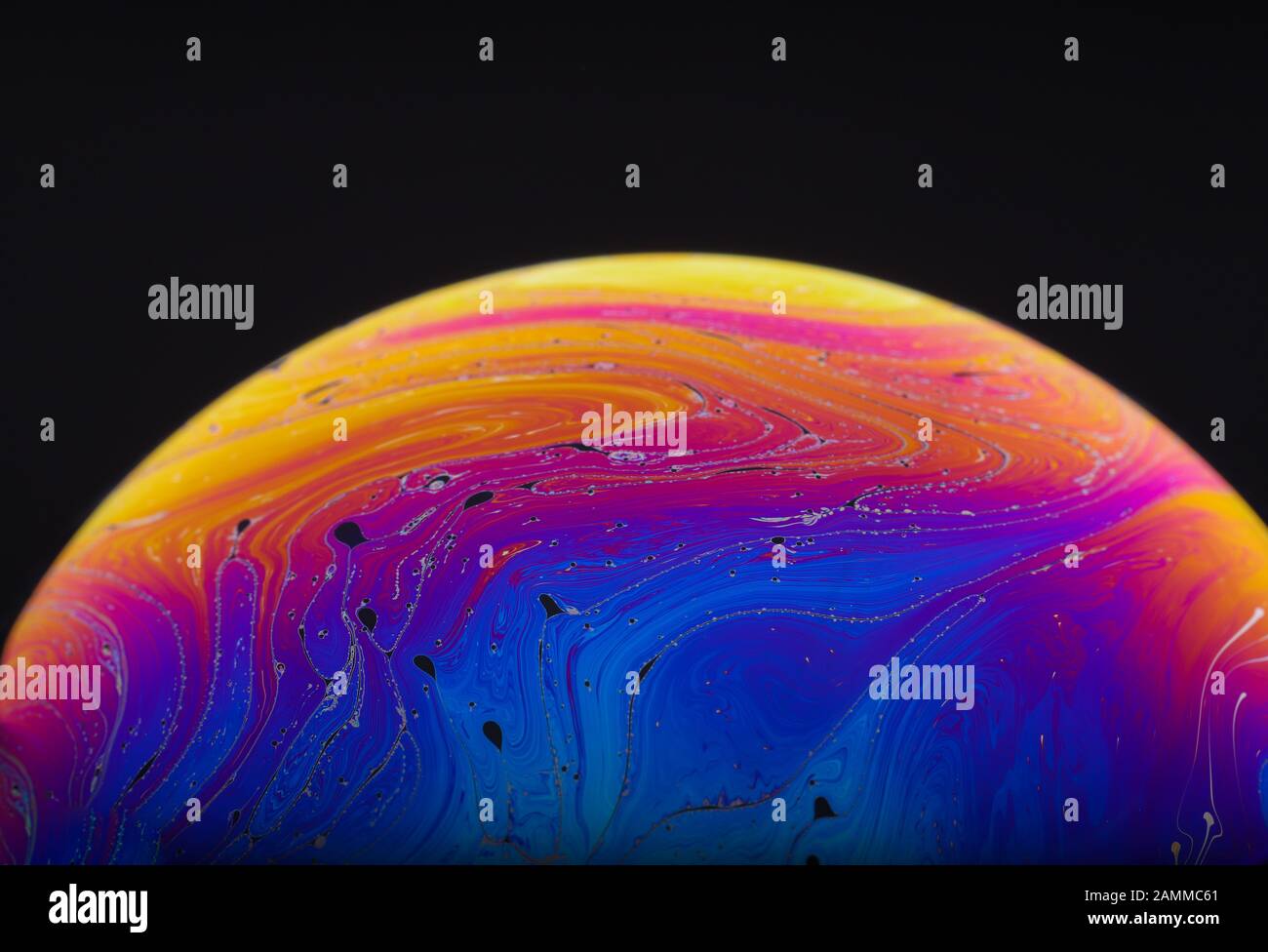 Gros plan sur l'arc-en-ciel psychédélique de couleurs mélangeant et tourbillonnant dans une bulle de savon pour ressembler à une galaxie ou une planète fantasy isolé un fond noir Banque D'Images