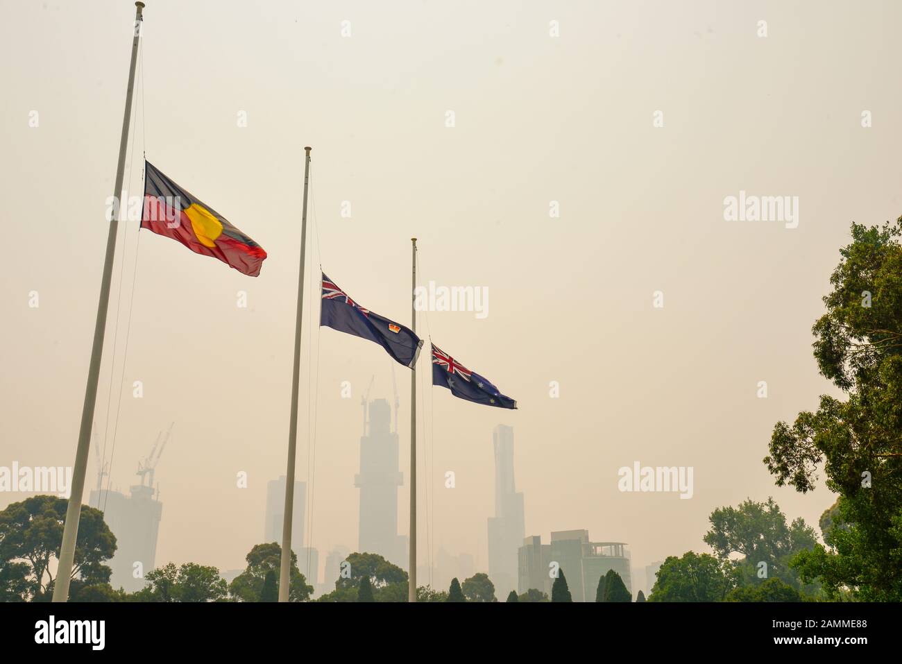 Drapeaux en berne avec la fumée provenant des feux de brousse dangereux santé couvrant la ville de Melbourne, Victoria, Australie Banque D'Images