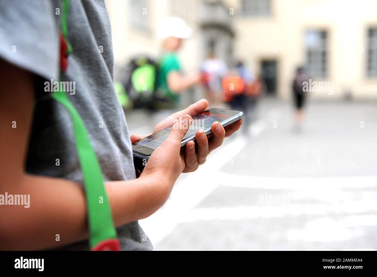 Image symbolique sur le thème "interdiction du téléphone mobile dans les écoles primaires": Un élève regarde la diplay de son smartphone dans l'aire de jeux d'une école primaire. [traduction automatique] Banque D'Images