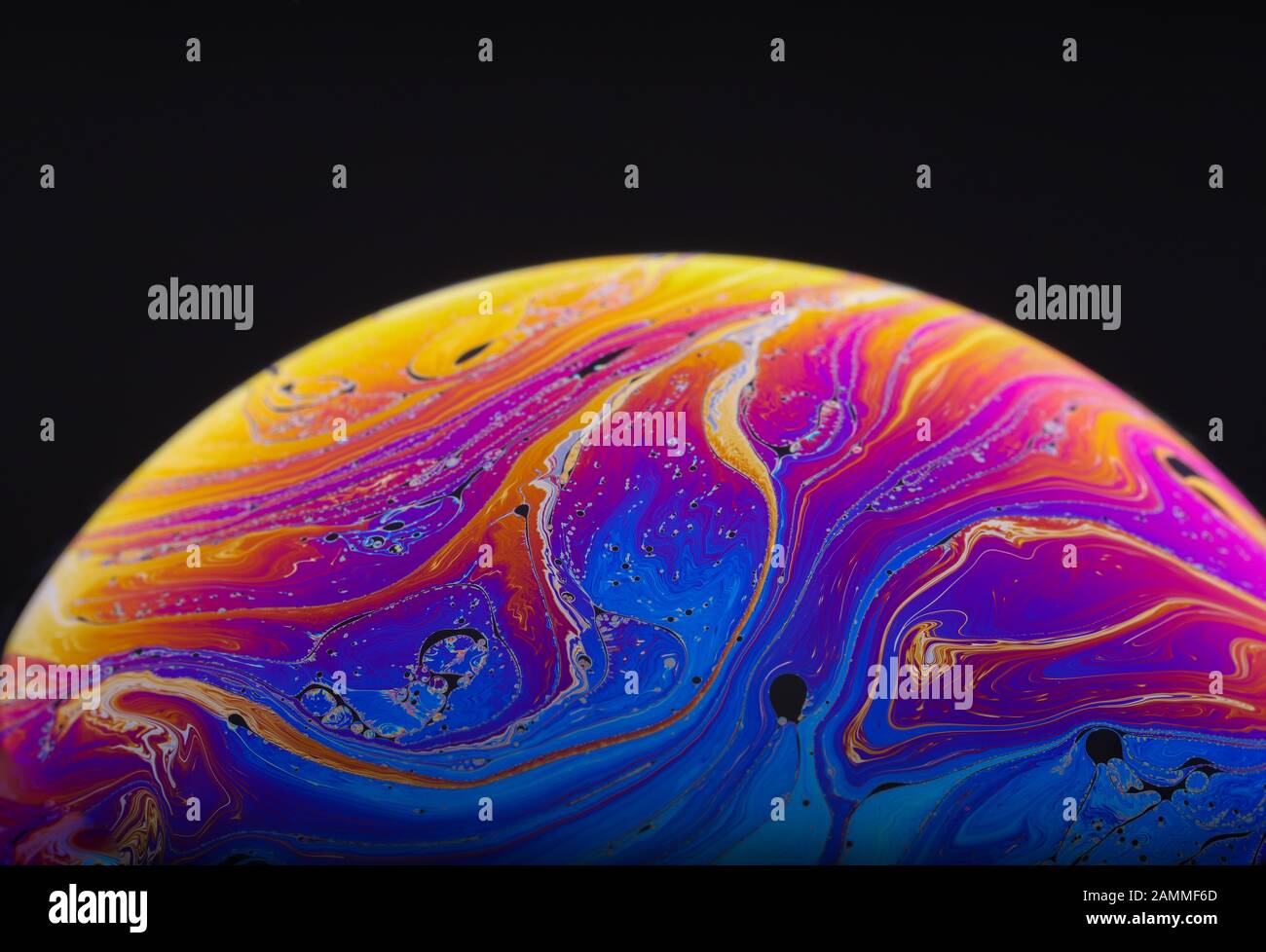 Gros plan sur l'arc-en-ciel psychédélique de couleurs mélangeant et tourbillonnant dans une bulle de savon pour ressembler à une galaxie ou une planète fantasy isolé un fond noir Banque D'Images