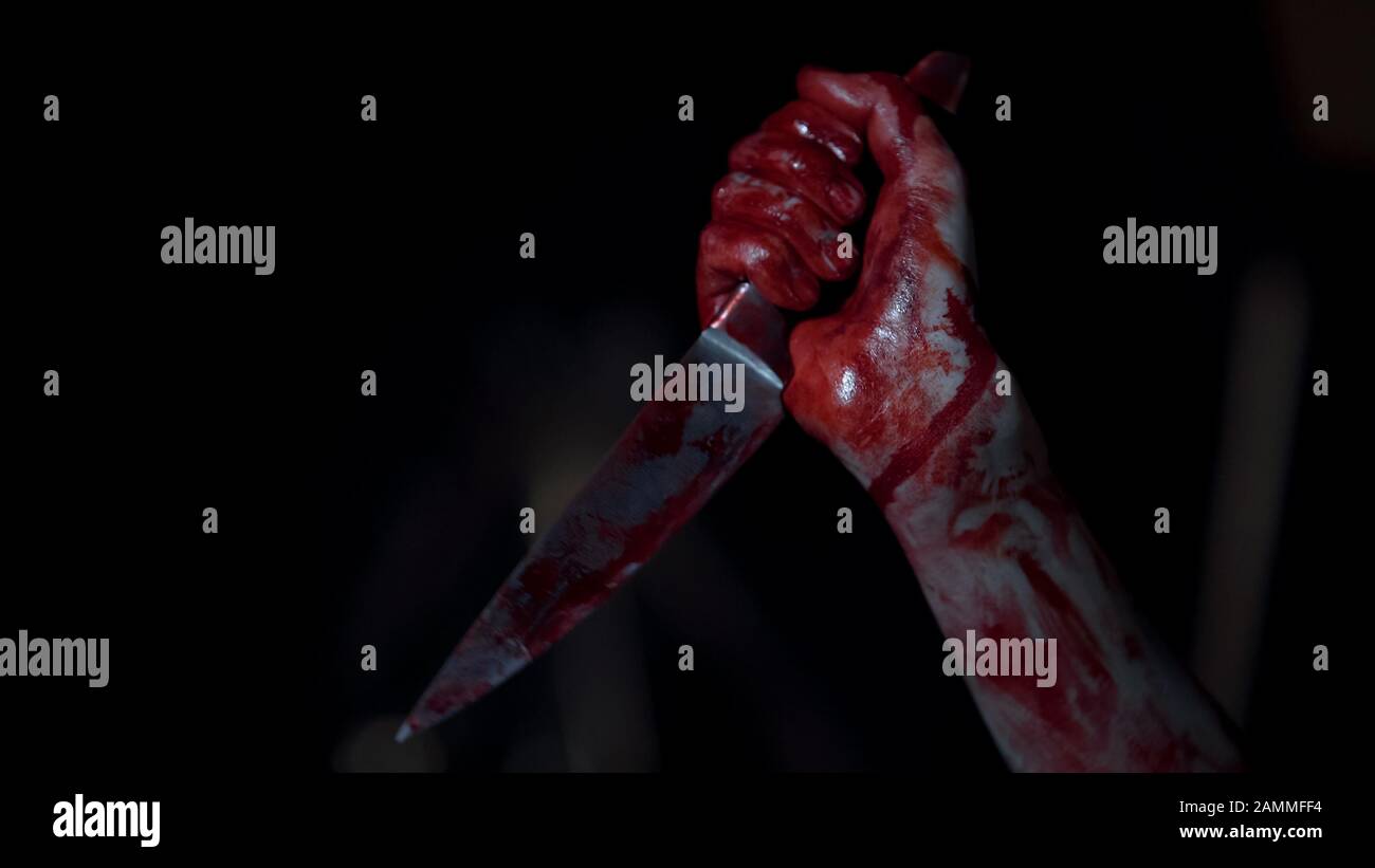 Couteau de préhension de tueur en série Mad recouvert de sang, mains de manac impitoyable Banque D'Images