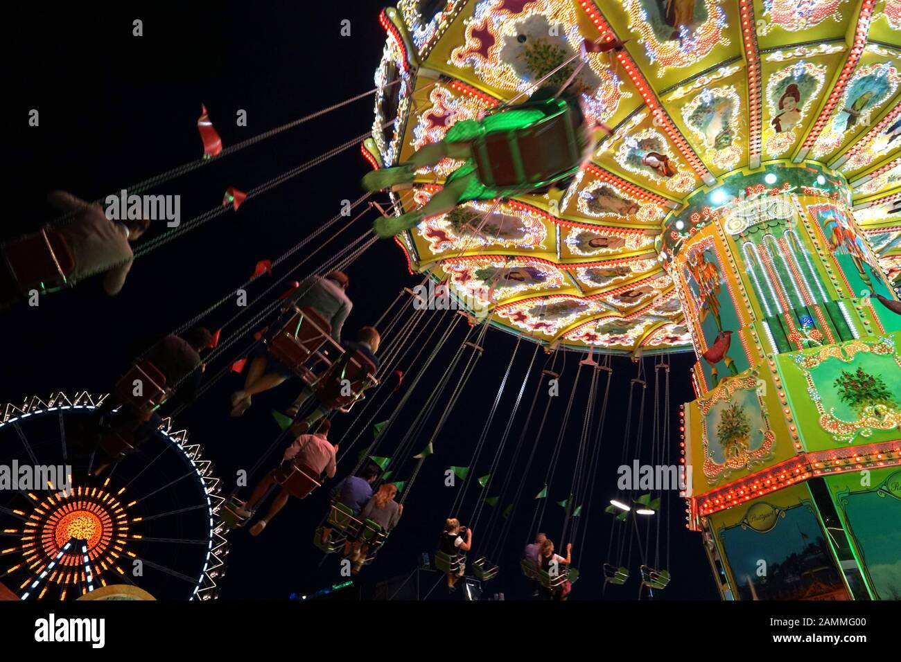 Carrousel à chaînes et roue ferris sur la Theresienwiese nocturne. [traduction automatique] Banque D'Images