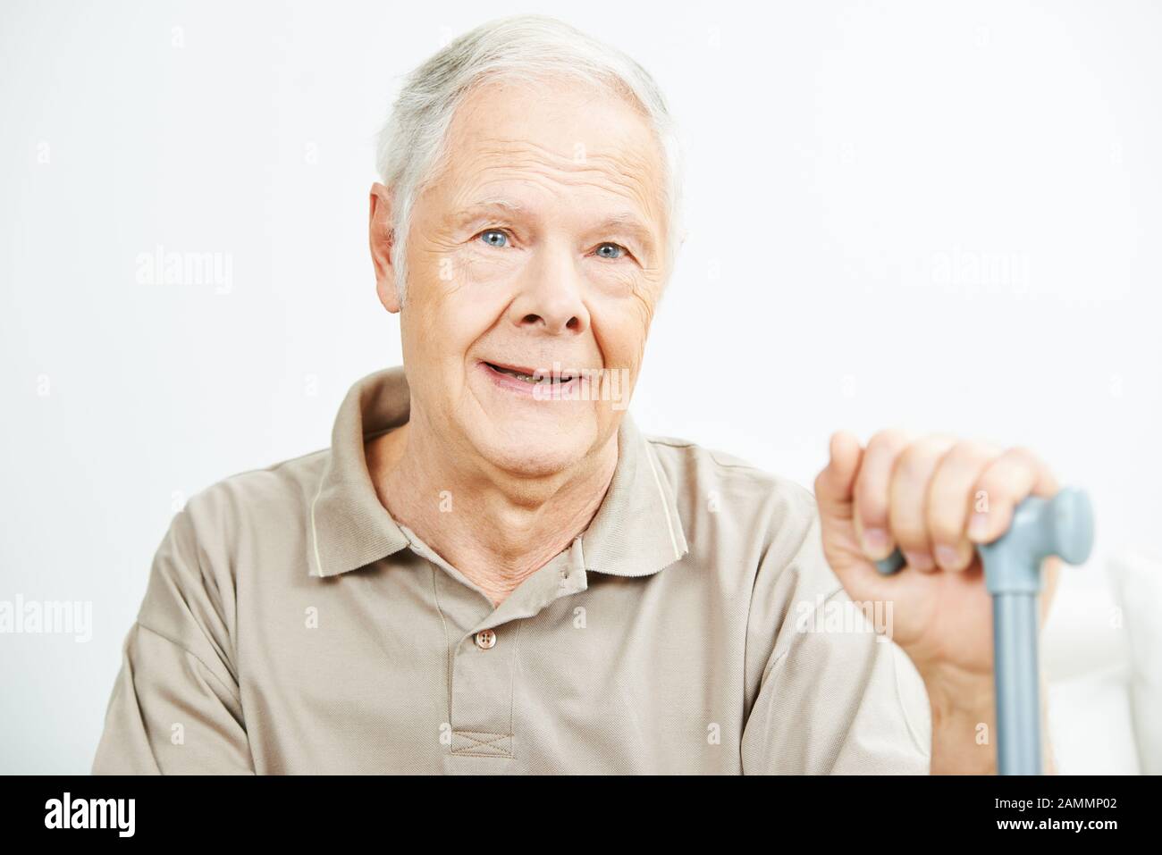 Un vieil homme souriant avec un bâton de utch est assis sans conteste dans la maison de retraite Banque D'Images