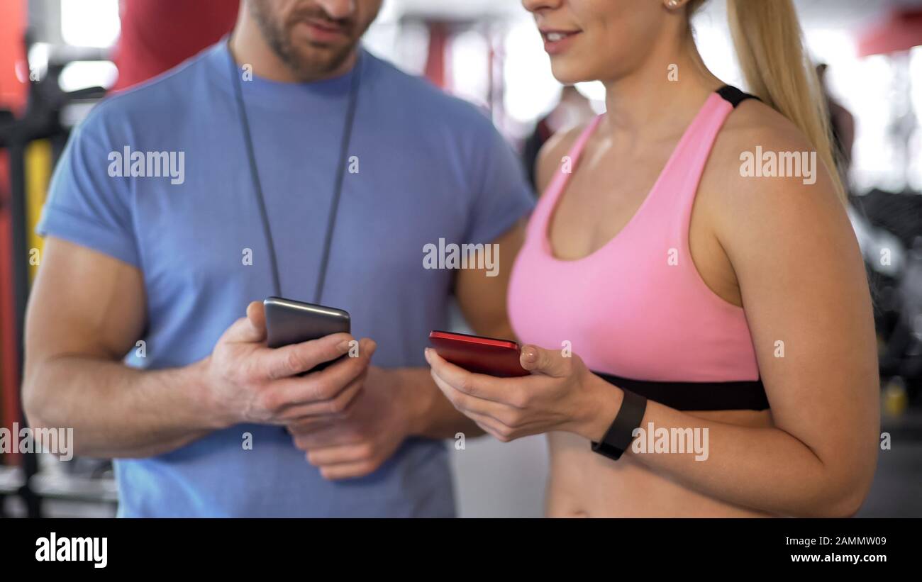 La femme fit une demande de suivi de ses résultats à son entraîneur personnel dans la salle de gym Banque D'Images